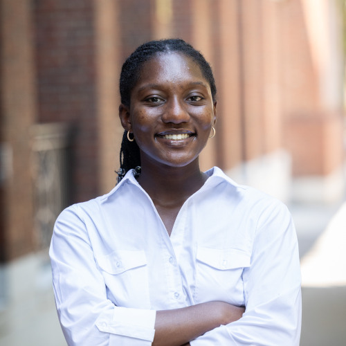 headshot of Emmanuela smiling in white shirt